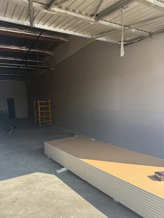 Drywall hung on the wall with a stack of sheets on the floor