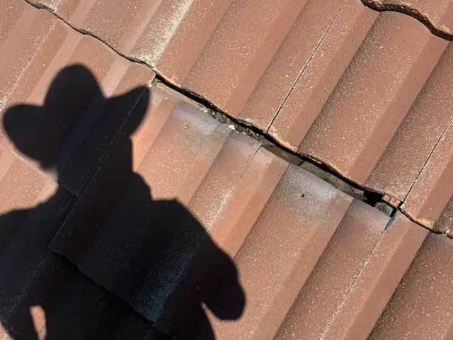 Cracked clay roof tile with a cowboy-hat shadow